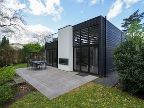 Ein modernes Haus mit Terrasse, Essbereich und Kamin.