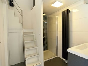Ein modernes Badezimmer mit Dusche, Badewanne und einer Treppe, die in einen anderen Raum führt.