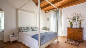 A four-poster bed with a white canopy, a wooden dresser with a mirror, and a small nightstand with a lamp. - Charming Cassaro apartment with private terrace (PALERMO)
