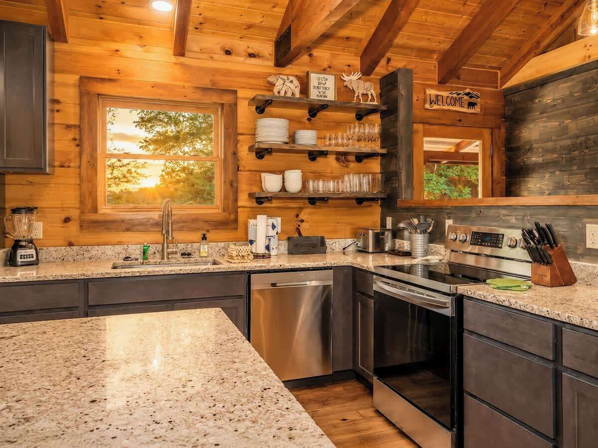 Une cuisine dotée de plans de travail en granit, d’appareils électroménagers en acier inoxydable et de meubles en bois.