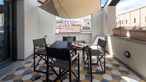 Ein Balkon mit Tisch, Stühlen, einer Pflanze und Blick auf Gebäude.