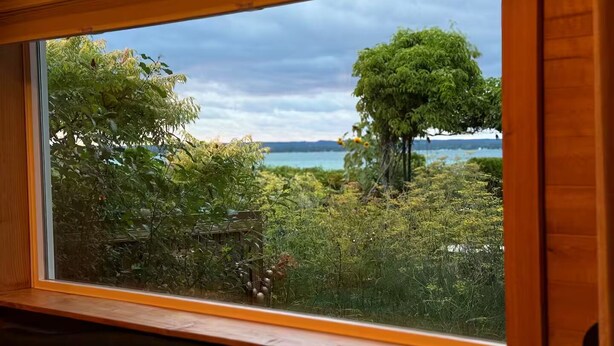 A window with a view of a lake and trees. - Blū House. (Williamsburg)