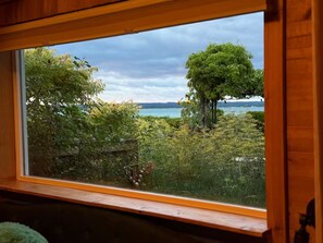 A window with a view of a lake and trees. - Blū House. (Williamsburg)