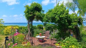 A garden with a table and chairs, surrounded by various plants and trees. - Blū House. (Williamsburg)