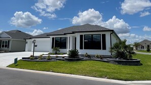 A single-story house with a garage, large windows, and a well-maintained lawn. - Open the Doors to Paradise in This Stunning New Retreat! (Sumterville)