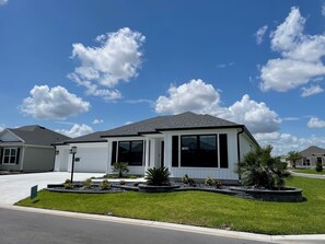 A single-story house with a garage, large windows, and a well-maintained lawn. - Open the Doors to Paradise in This Stunning New Retreat! (Sumterville)