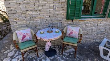 A stone wall with a window and a table with chairs.