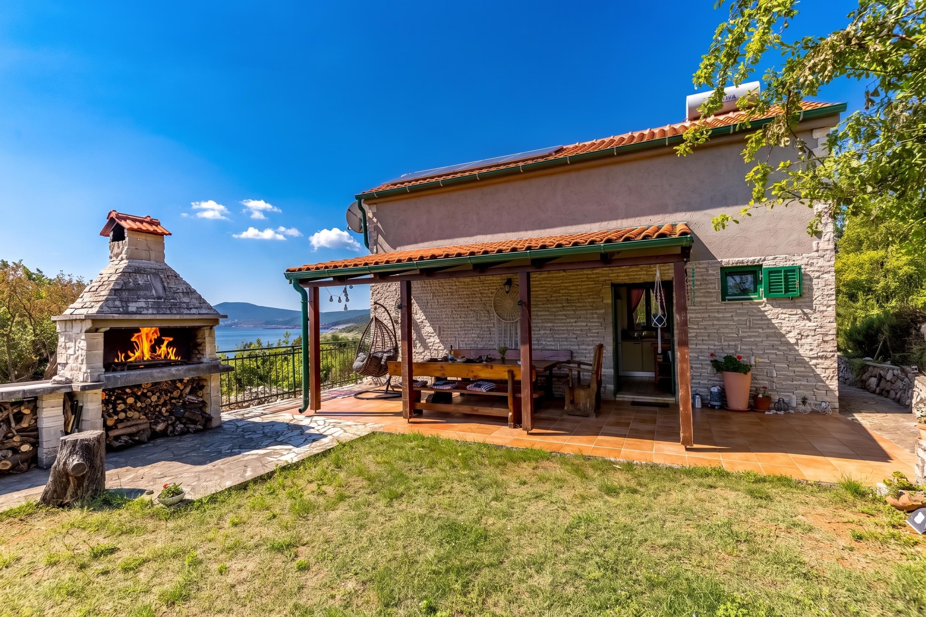 Una casa de piedra con un patio, mobiliario exterior y un estufa de leña.
