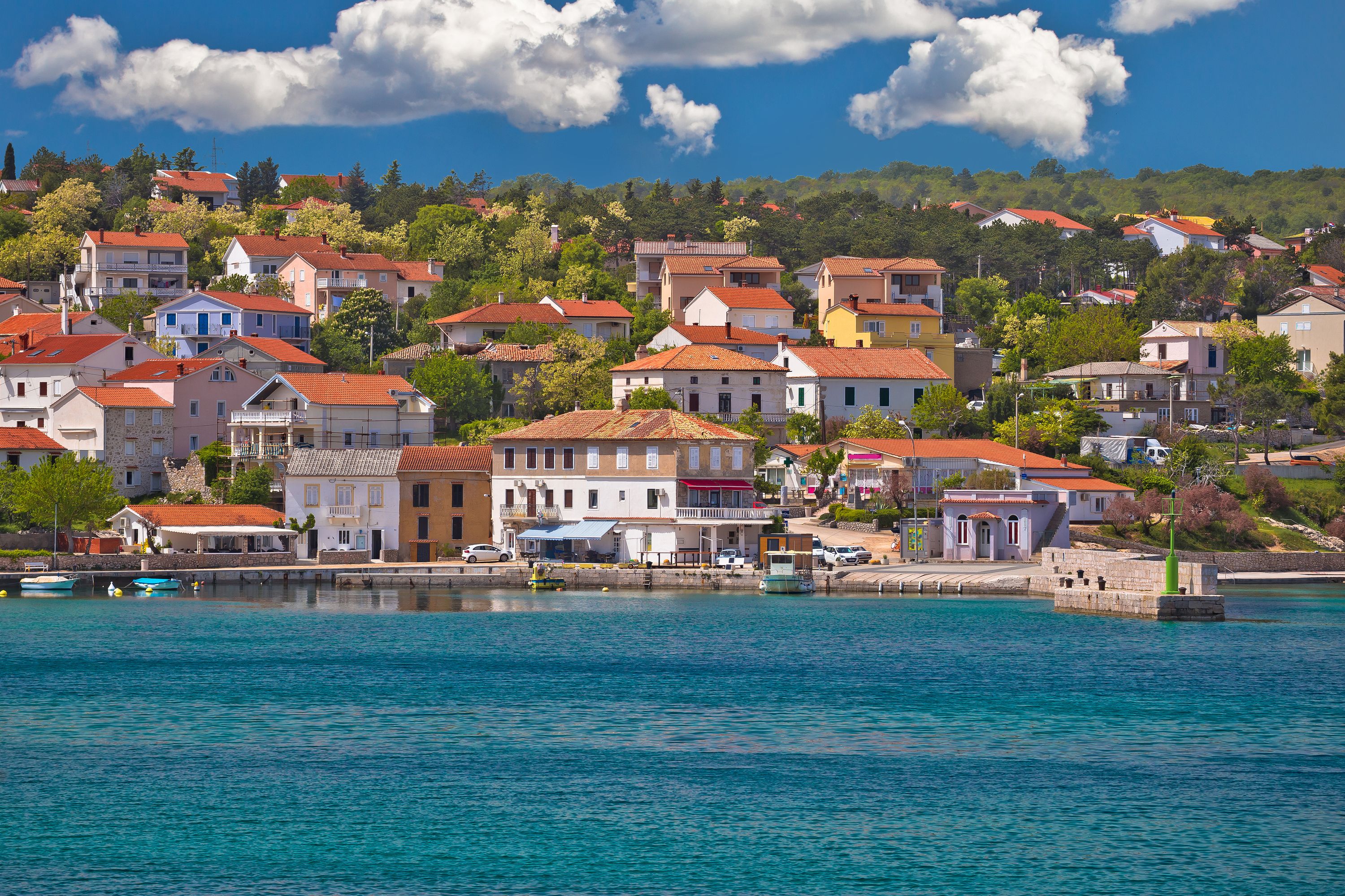A coastal town with buildings along the waterfront, a clear sky, and calm sea.
