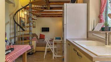 A compact kitchen with a refrigerator, a sink, and a dining area with a table and chairs.