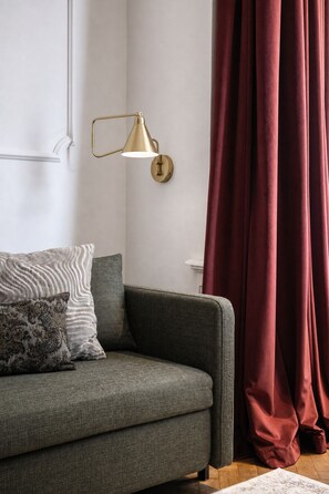 A modern living room with a sofa, a wall-mounted lamp, and a curtain. - Elegant Paris Ave apartment with a Terrace (Praha 1)