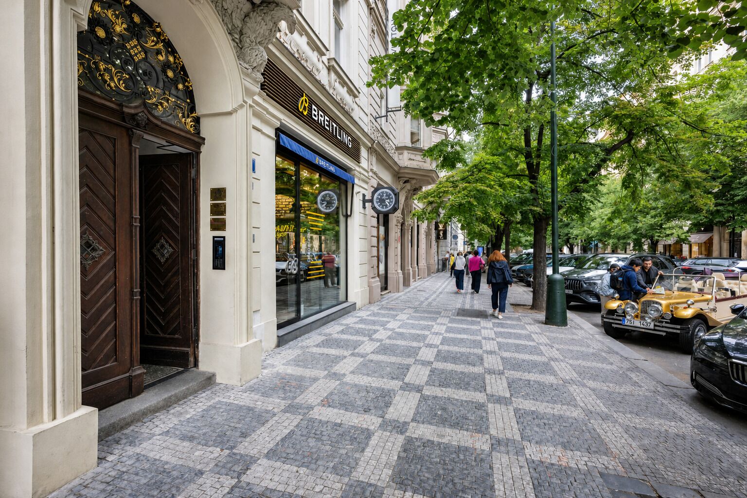 Une rue avec un trottoir pour les piétons, une horloge et des voitures garées.