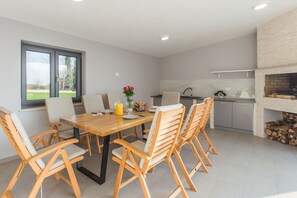 Eine moderne Küche mit Essbereich, großen Fenstern und einem Kamin.