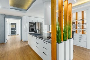Eine moderne Küche mit weißen Schränken, einer zentralen Kochinsel und einer Wand mit Holzvertäfelung.