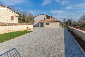 Ein modernes Haus mit befestigter Auffahrt, Steinmauern und einem kleinen Garten.