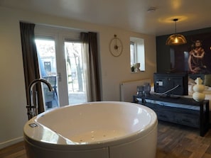 A modern bathroom with a freestanding bathtub, a vanity, and a television. - Comfort Connecting Room 10 (Otterlo)