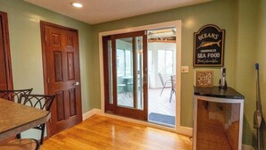 A kitchen with a wooden table, a sliding glass door leading to a patio, and a sign for 'OCEANS Charbroiled Sea Food.'