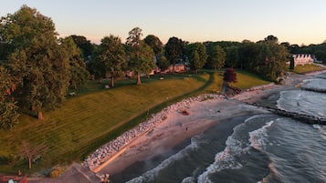 A coastal landscape with a grassy area, trees, and a beach with waves.