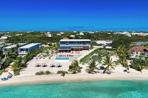 A beachfront property with a swimming pool, multiple lounge chairs, and a clear view of the ocean. - Ambra Beach Club and Restaurant (Providenciales)