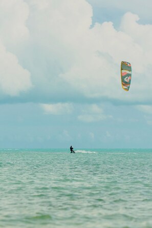 A person windsurfing on a calm sea with a colorful kite. - Ambra Beach Club and Restaurant (Providenciales)