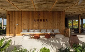 A wooden wall with the word 'AMBRA' and a bench with cushions.