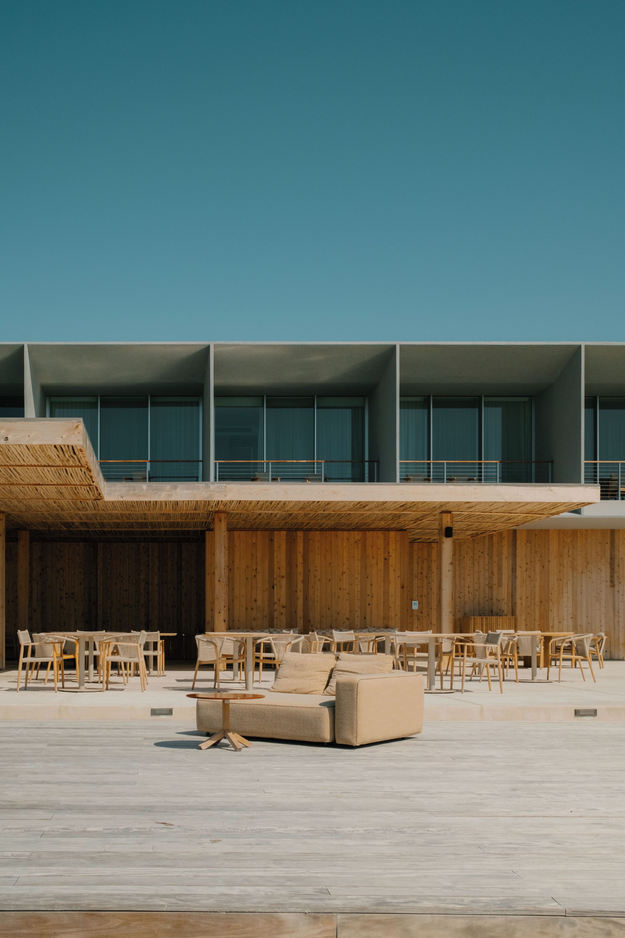 A modern outdoor seating area with wooden furniture and a concrete floor.