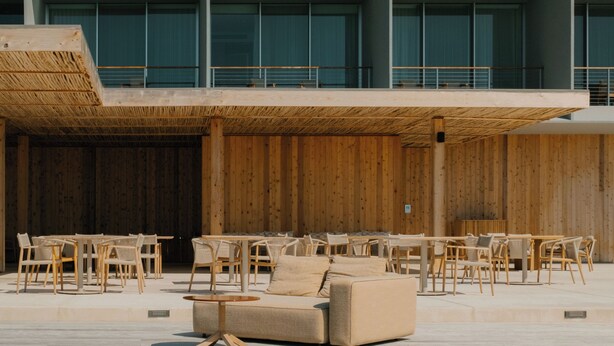 Un espacio exterior moderno con mobiliario de madera y suelo de hormigón.