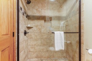 A glass-enclosed shower with beige tiles, a towel rack, and a wooden door. - Close to Skiing & Town, Spacious 2BR + Loft (Breckenridge)