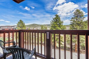 A wooden deck with a view of a residential area, a thermometer, and two chairs. - Ski-In Mountain Condo | Perfect for Families & Groups (Breckenridge)