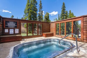 A hot tub with a wooden deck, a sign with hot tub rules, and a view of trees. - Ski-In Mountain Condo | Perfect for Families & Groups (Breckenridge)