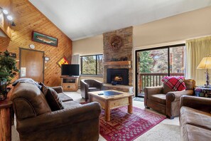 A cozy living room with leather sofas, a fireplace, a television, and a large window. - Ski-In Mountain Condo | Perfect for Families & Groups (Breckenridge)
