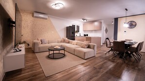 Una sala moderna con un sofá modular, una mesa de centro redonda y un comedor con mesa y sillas.