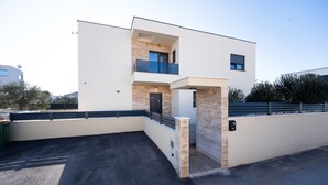 Un edificio moderno de dos pisos con techo plano, balcón y fachada de piedra.