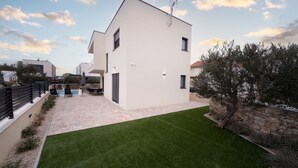 Una casa moderna de dos pisos con techo plano, patio empedrado y césped cuidado.