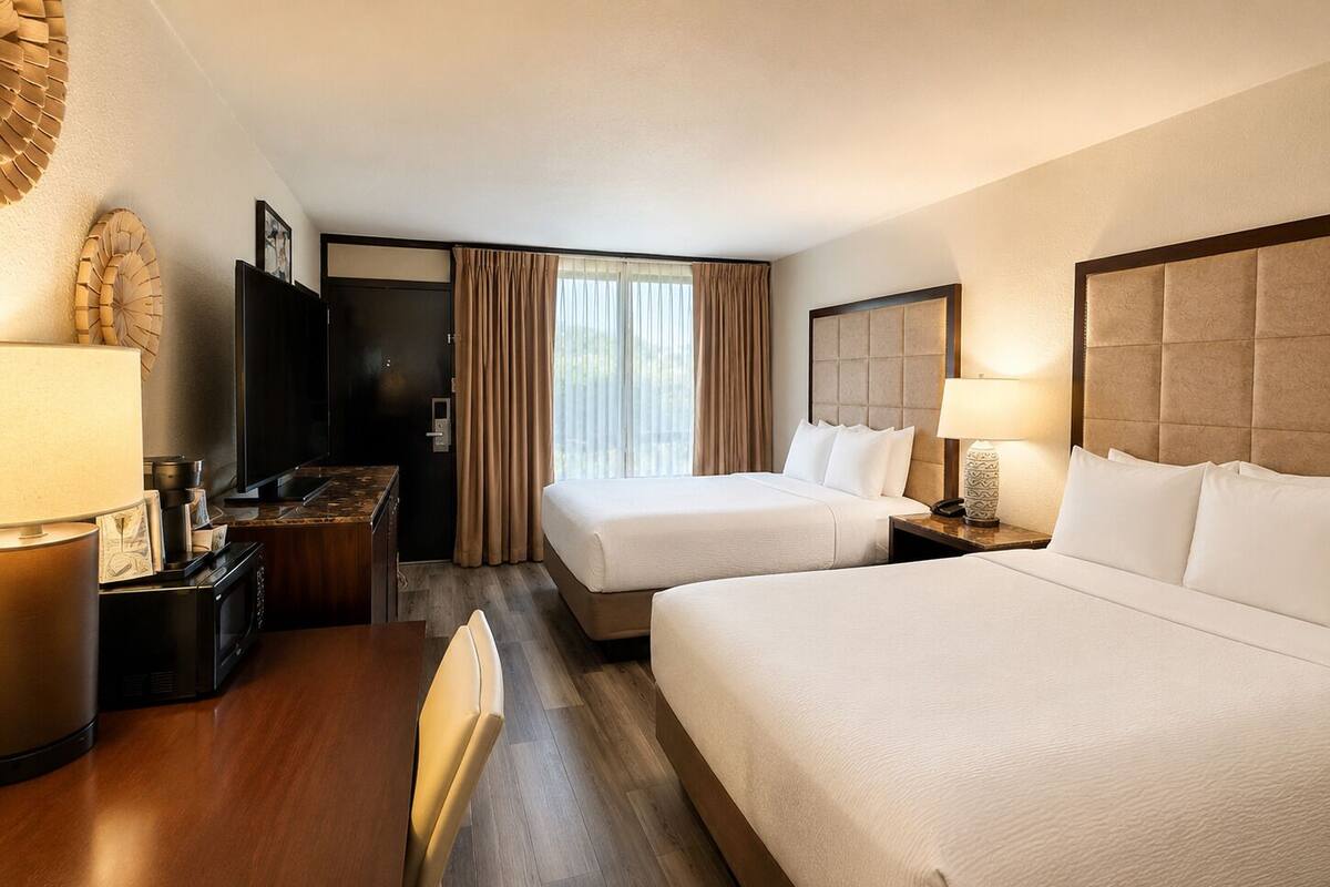 Ein Hotelzimmer mit zwei Betten, einem Schreibtisch, einem Fernseher und einer Minibar.