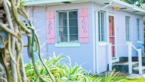 Een huis met roze luiken, een witte deur en een raam waarop een 'B' staat.