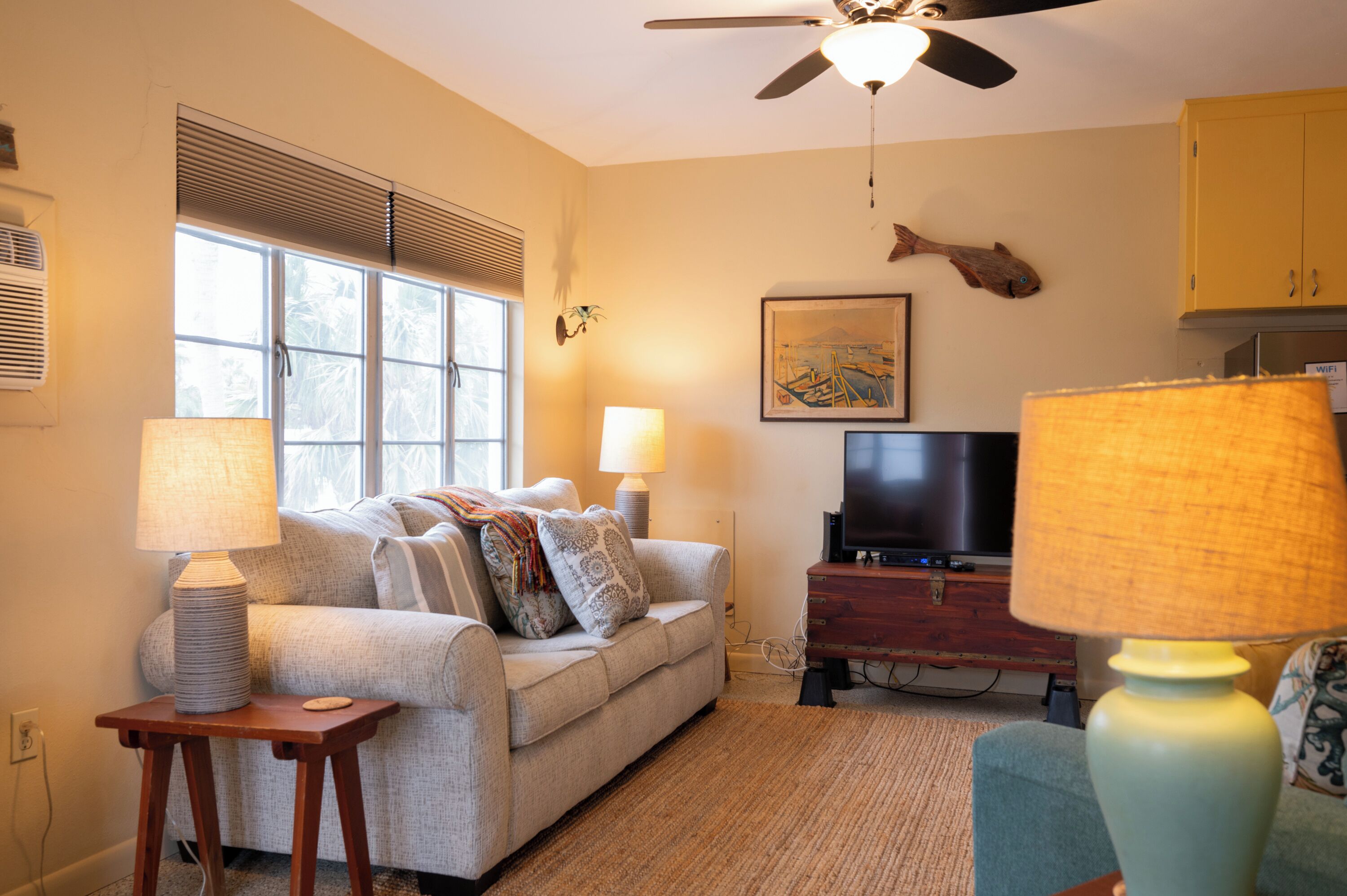 A living room with a sofa, two lamps, a TV, and a ceiling fan.