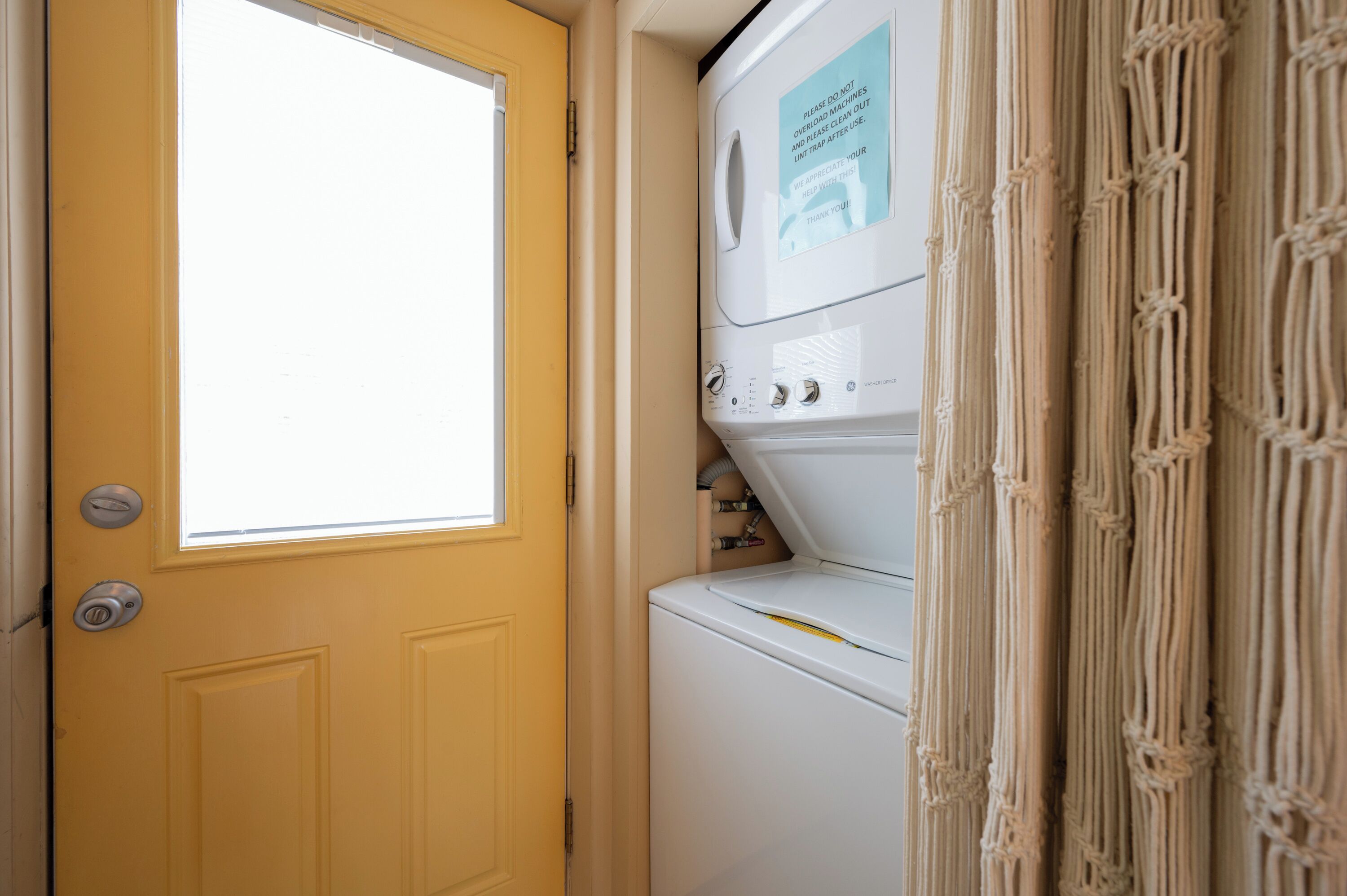 A laundry room with a yellow door, a washing machine, and a dryer.