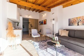 Ein modernes Wohnzimmer mit einer Couch, Sesseln, einem Couchtisch und einem Bild an der Wand.