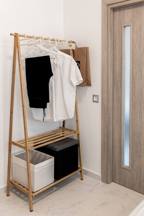 Ein Kleiderständer aus Holz mit Kleidung und Aufbewahrungsboxen an einer Wand.