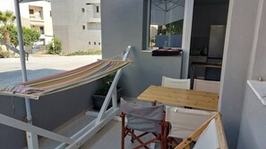 Ein Balkon mit einer Hängematte, einem Holztisch und einem Stuhl.