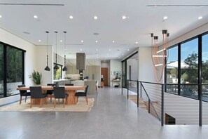 A modern interior with a dining area, kitchen, and large windows. - Round Valley Residence - Sherman Oaks Hillside Retreat with Pool and Spa (Sherman Oaks, Los Angeles)