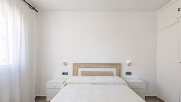A minimalist bedroom with a bed, two bedside tables, a bench, and a wardrobe. - Penthouse with Private Sun Deck, BBQ, and Beach (Cunit)