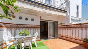 A patio with a table and chairs, a green artificial turf, and decorative tiles. - Penthouse with Private Sun Deck, BBQ, and Beach (Cunit)