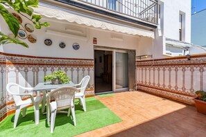 A patio with a table and chairs, a green artificial turf, and decorative tiles. - Penthouse with Private Sun Deck, BBQ, and Beach (Cunit)
