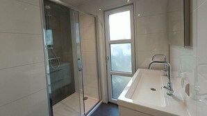 A modern bathroom with a glass-enclosed shower, a sink with a mirror, and a window providing natural light. - Holiday Home in Otterlo With Terrace (Otterlo)