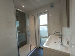 A modern bathroom with a glass-enclosed shower, a sink with a mirror, and a window providing natural light. - Holiday Home in Otterlo With Terrace (Otterlo)