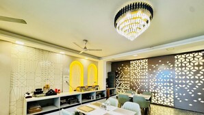 A modern dining area with a ceiling fan, a chandelier, and a geometric wall design. - the royal oak sec 40 hotel gurgaon (Gurugram)