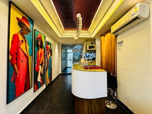 A hotel lobby with a reception desk, a wall-mounted television, and a ceiling with a textured pattern. - the royal oak sec 40 hotel gurgaon (Gurugram)