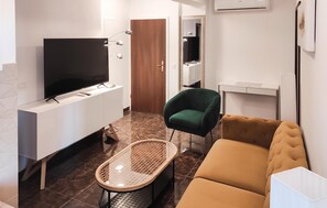 A modern living room with a flat-screen TV, a green chair, a brown sofa, and a small table. - 2 bedroom nice apartment in Okrug Gornji (Okrug Gornji)